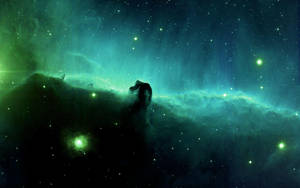 一個發光的綠色和藍綠色星雲，在星空背景下有一個黑暗的宇宙柱狀剪影。