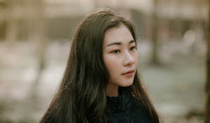 長黑髮的年輕女性在戶外若有所思地凝視。