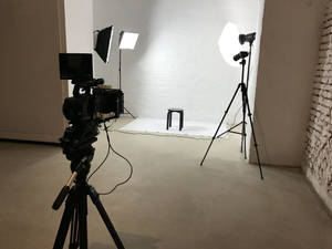 影片製作工作室，白色背景上有相機燈光和凳子。