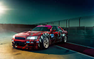 紅色飄移車在星空下夜間賽道上疾馳，車頭燈閃閃發光。 — 日產 Skyline GTR R33 壁紙