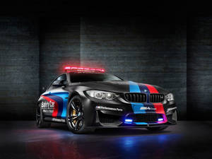 黑色BMW M4 Coupe安全車，在黑暗的攝影棚中帶有紅色和藍色條紋及閃爍燈光。