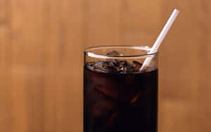 木面上有冰塊和飲管的冰凍可樂杯。 — 咖啡 壁紙