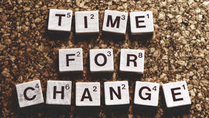 白色 Scrabble 字母磚在軟木背景上拼出 time for change。