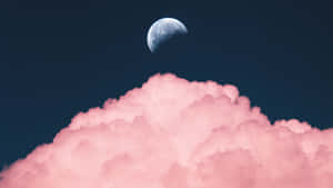 深藍色夜空中粉紅雲朵上方的新月
