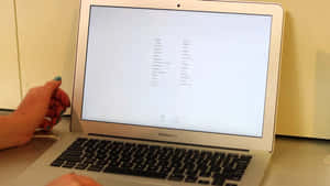 手靠近銀色MacBook Air，螢幕上顯示語言選項。