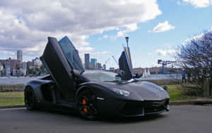 啞黑色林寶堅尼Aventador，車門打開，在海濱靠近城市天際線，日落時分。