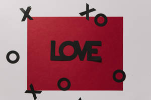 紅色紙張上有黑色字母 LOVE，周圍有 X 和 O 剪紙。