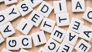木質背景上帶有字母的 Scrabble 遊戲字母磚。 — 木紋 壁紙