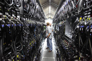 兩名男子穿過一個裝滿電腦設備的伺服器機房。