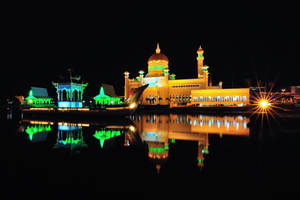 夜晚，燈光清真寺和亭閣倒映在水中，帶有星爆光芒。 — 建築 壁紙