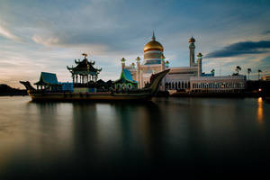 金色圓頂清真寺和船形亭子在黃昏時分倒映在水中 — 日落天空 壁紙