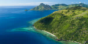 晴朗天空下，鬱鬱蔥蔥的綠色島嶼、碧綠海水和珊瑚礁。 — 島嶼 壁紙