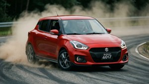 紅色鈴木 Swift 在潮濕林間道路上飄移，輪胎揚起灰塵