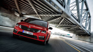 紅色Skoda Octavia RS在高速公路上的鋼橋下疾馳。