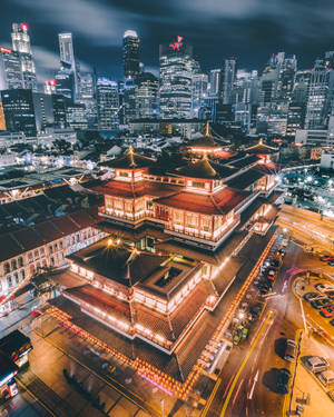 夜晚發光的傳統寺廟，被城市燈光和車流軌跡包圍。
