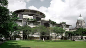現代弧形屋頂建築，旁邊是歷史悠久的圓頂建築，天空多雲。