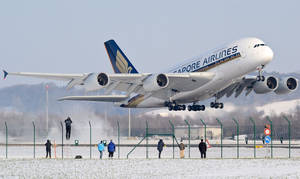 一架大型白色飛機從積雪跑道起飛，人們在觀看。 — 冬天 壁紙