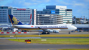 新加坡航空貨運飛機在機場跑道上，背景有建築物。