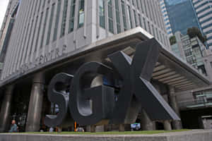 SGX標誌雕塑矗立在現代商業大樓前，有行人經過。