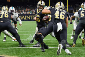 NFL美式足球員在夜間比賽中於燈光球場上奮戰。 — 聖人 GIF 壁紙