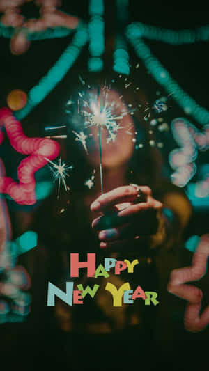 手拿煙花棒，背景有彩色散景燈光和Happy New Year文字。 — 手機 壁紙