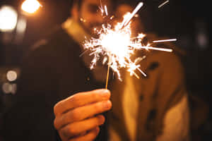 夜晚手持閃爍的煙火，背景燈光模糊。 — 聖誕快樂 GIF 壁紙