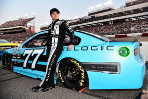 NASCAR車手在擠滿觀眾的賽道上靠著他的藍色賽車。 — 汽車 壁紙
