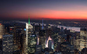黃昏時分的紐約市天際線，燈火通明的建築物和色彩繽紛的天空。