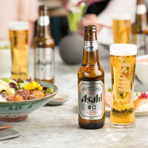 Asahi啤酒瓶和玻璃杯，桌上放有日本料理。 — 日本 壁紙