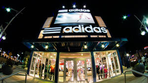 現代adidas零售店在夜晚透過玻璃窗和發光標誌照明。 — Adidas GIF 壁紙