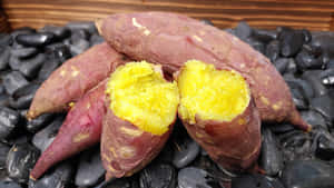 烤番薯，金黃色果肉，放在黑色鵝卵石上 — 精細 壁紙