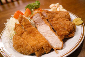 切片酥脆吉列豬扒，配椰菜、番茄和配菜，盛於碟中。 — 美食 壁紙