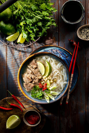 越南河粉碗，配有牛肉、青檸、香草和辣椒，放在木桌上