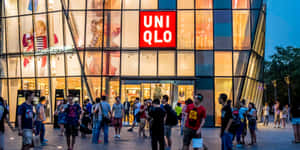 人群在黃昏時聚集在一間現代玻璃Uniqlo店鋪外。 — 暮光 壁紙