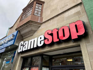 陰天下，石造外牆上帶有紅白招牌的GameStop店鋪外觀。 — 遊戲 壁紙