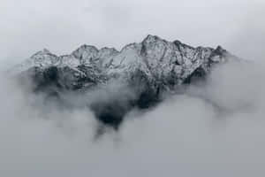 白雪覆蓋的山峰在灰暗的日子裡從濃密的雲層中浮現。