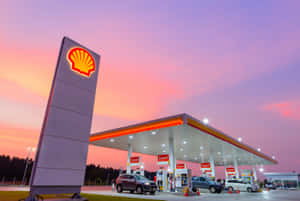 日落時分的Shell加油站，汽車在發光的燈光下加油。
