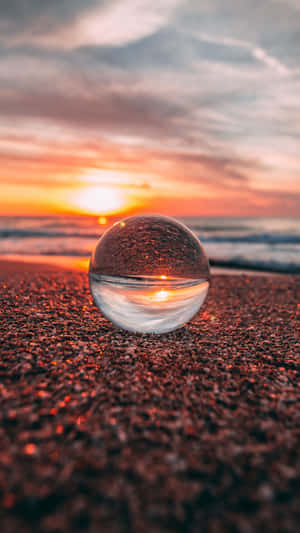 海灘上的玻璃球反射海洋波浪上的日落 — 海灘 壁紙