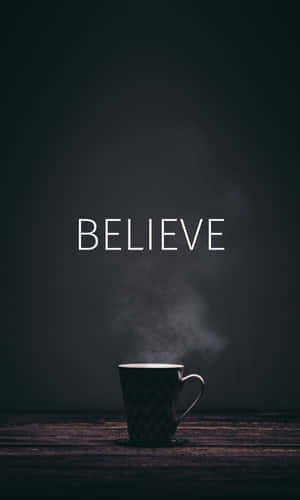 一個冒煙的馬克杯，上方有「BELIEVE」字樣，置於木質表面。 — Realme Pad 2 壁紙