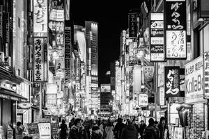 夜晚擁擠的東京街道黑白照片，帶有發光招牌。