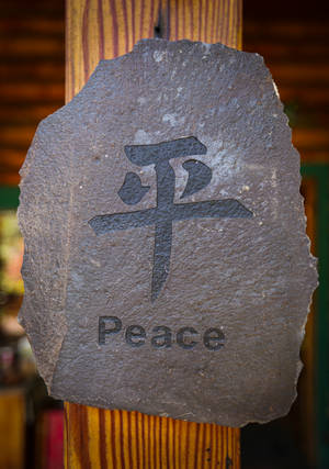 一塊石牌，上面刻有漢字「平和」和英文單詞「peace」。 — Oppo Pad 5 Pro 壁紙