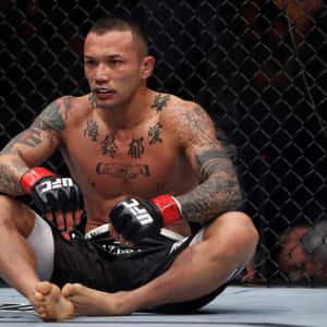 一位有紋身的MMA選手在比賽後坐在八角籠地上。 — 動漫打鬥 壁紙