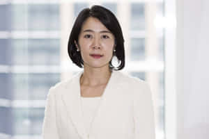 專業女性穿著白色西裝外套站在辦公室窗邊