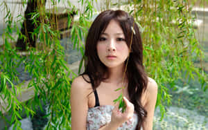 年輕女子在花園水邊手持柳葉