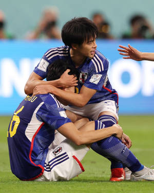 兩名日本足球運動員在草地上慶祝入球。 — 日本 壁紙