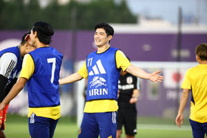 身穿藍黃裝備的足球運動員在草地上訓練時大笑。 — 日本 壁紙