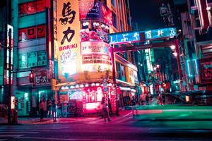 霓虹燈照亮夜晚的東京街道，發光的招牌和潮濕人行道上的倒影。 — 日本 壁紙