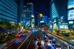夜間城市街道，有發光的建築物和移動的車燈。