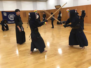 兩名全副裝備的劍道練習者在室內以木劍對練。 — 日本 壁紙