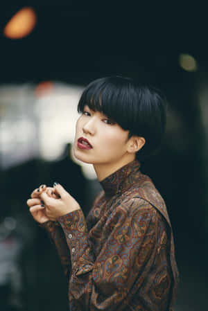 城市環境中，穿著佩斯利襯衫、短黑髮、紅唇的女性